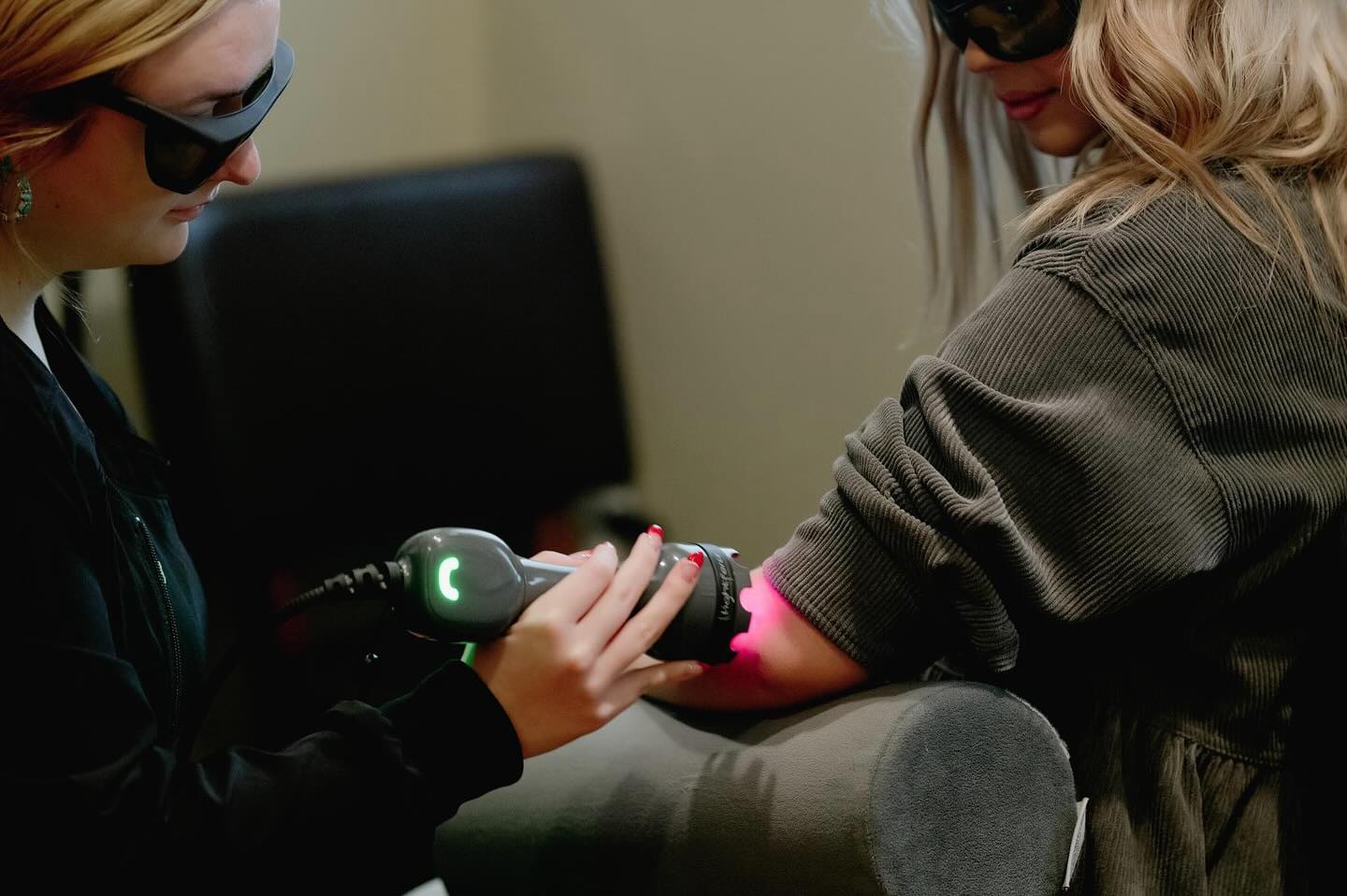 Clinician applying deep tissue laser therapy to patient's arm using handheld device